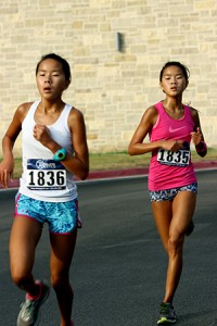 Twin medals: Sophomores Kerri and Kylie Welch run one behind another on Aug. 25 at the Melon Run.