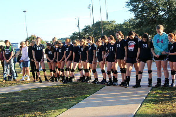 Volleyball players bow their heads in prayer during See You at the Pole.
