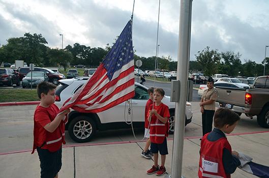 Students from Timberwood Elementary raise the flag.