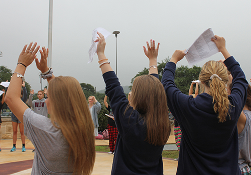 Students raise their hands after they finish a prayer.