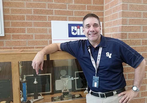Mr. Donna poses in front of the trophies in the front offices.