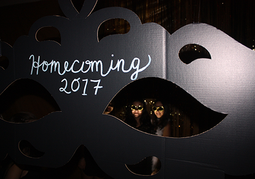 Students take photos behind the Homecoming mask cut out last Saturday.