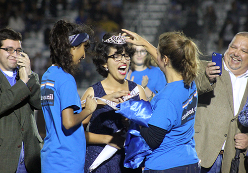 With brother Michael and her dad celebrating, senior Maria Rocha receives her crown as homecoming queen Sept. 29 during halftime of the East Central game.