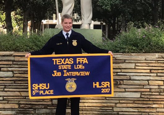 Junior Clayton Elbel poses with his banner from winning fifth place at the Texas FFA state LDEs Job Interview competition Dec. 2. Elbel completed seven sections of the competition over the span of multiple days.
