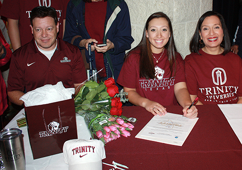 Raquel Hill sit in between her parents, signing her letter of intent. She will golf at Trinity University. Its a really small school, Hill said. I really liked the coach and atmosphere. 
