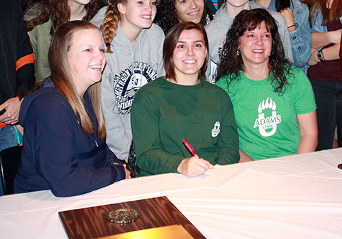 Avery Wilson sits in between Coach Kari Osborne  and her mother. She signed with Adams State University to swim. I love the location, she said. It has my major of environmental science too.