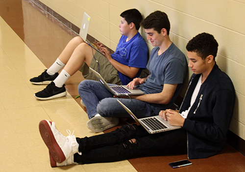 Freshmen Hamilton Moye, Brandon Salvaggio and Austin Stiefel work on their World Geography project outside of B-Wing on March 27.