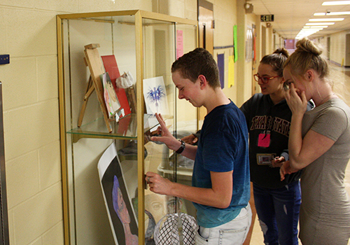 Freshman McKay Rush, junior Riley Sherrill and sophomore Anna Lambson arrange the art display cases outside of B-wing after finishing recent projects on March 28.