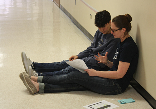 Junior Sidney Naud and capstone teacher Cory DeBoest have a writing conference in the hall during March 9.