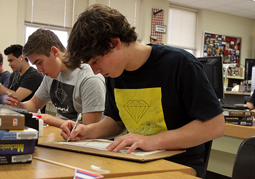 Sophomores Eli Chappell and Josh Pena work on finishing their delta dart project for their engineering class on March 19.