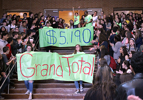 With FACS sponsor Tina Olcott celebrating at the top of the stair, FACS representative carry the banners announcing the grand total of $5,190 raised during SPUD Week. That exceeded the goal of $5,000. SPUD (Students Performing Unselfish Deeds) week included spirit nights at Specht Store and Ay Chiwawa, Taco Tuesday with ROTC, a faculty-student basketball game and the annual dodgeball tournament, all to raise funds for cancer survivor Sequoia White and the Leukemia Lymphoma Society.