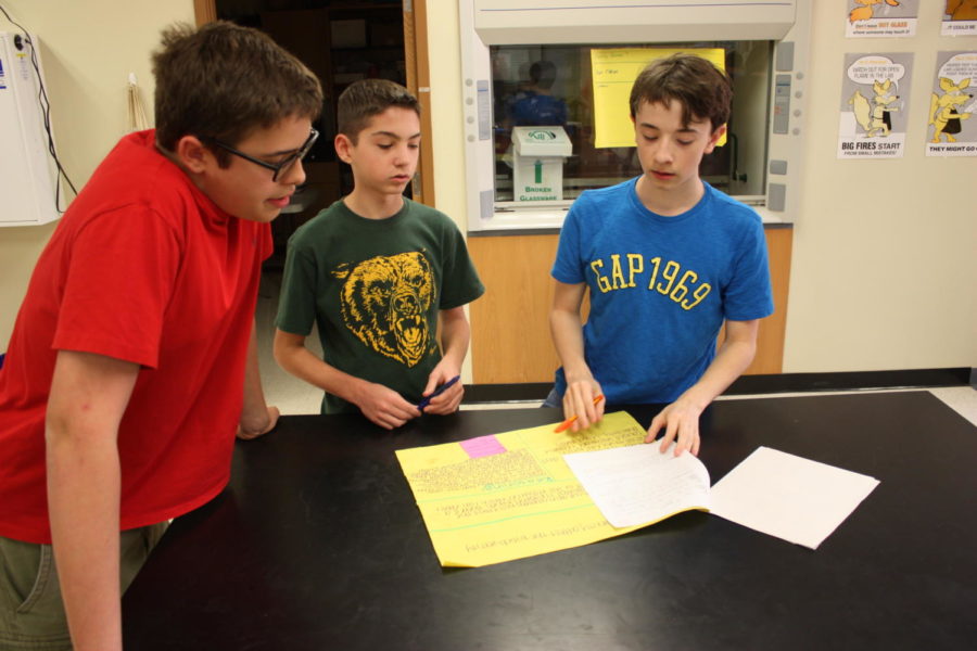 Freshmen Joshua Harshbarger, Colin Fuller and Kasey Wheeler grade a poster in biology on April 25.