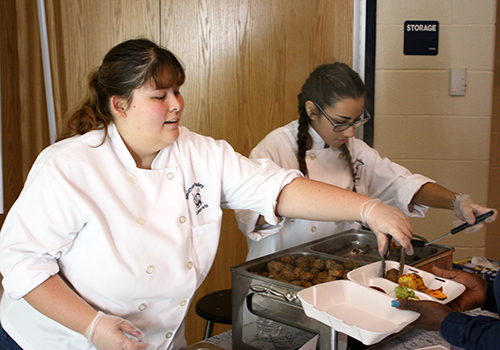 Senior Chantelle Cresswell and Isaelle Ramirez serve Barbacue beef meatballs and mini chicken and cheese enchiladas.
