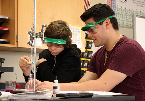 Sophomore Austin Kenwisher and Michael Freitas slowly drip chemicals from the burette to make a solution during their titration lab on May 22.
