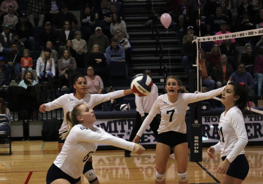 Players Tara McLeod, Tanyse Moehrig-Woodard, and Maddie Dennis look on as Junior Erin Feely hits the ball on Oct. 22 