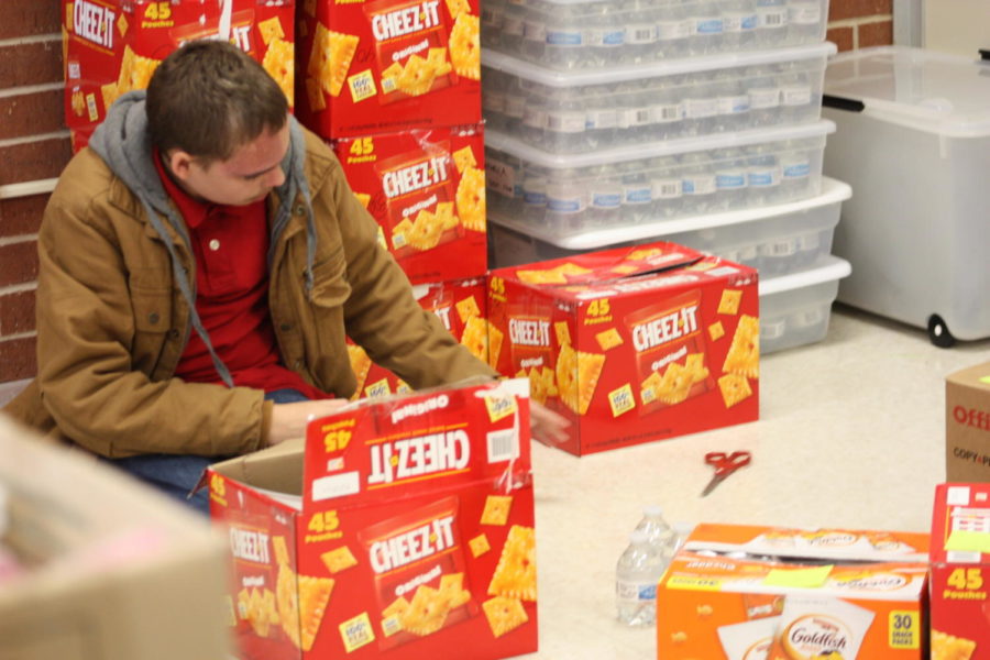 Getting ready for testing week, student packs cheez-its into classroom preparation boxes.