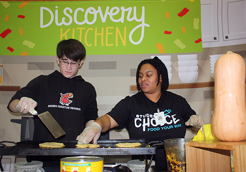 With guidance from Jasmynn Lahner of Child Nutrition, junior Levi Wheeler practices making quesadillas with butternut squash on Nov. 6. Those walking through the senior dining hall got free samples.