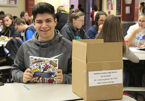 Supporting the art department, senior David Yanez sells coloring books during lunch in the cafeteria.