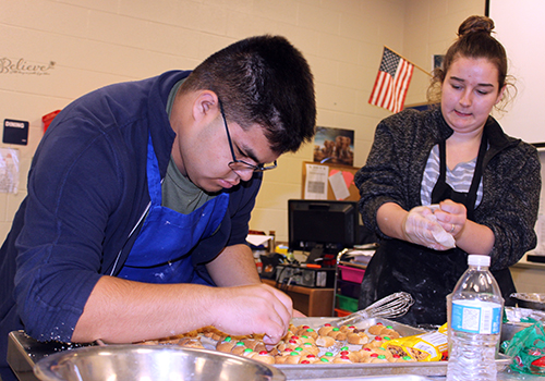 With final touches to their snowman cookies, juniors Diego Quinones and Kristen Mueller get ready to present their entry for their culinary class cookie contest Dec. 19.  Mueller found the recipe at tastegood.com. I wanted to get out of my comfort zone of decorating sugar cookies and challenge myself, she said.