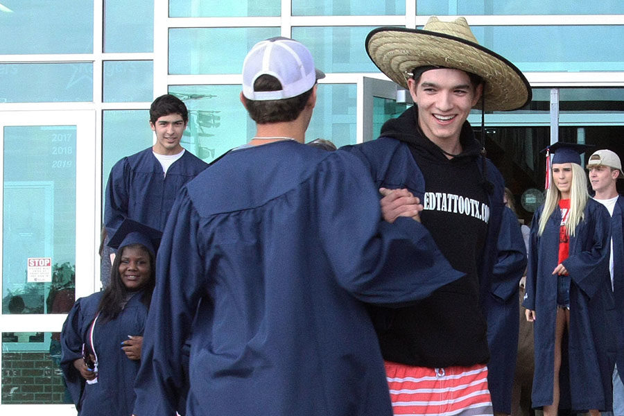 Justin Trevino greets a friend in front of the school after the senior walk today.