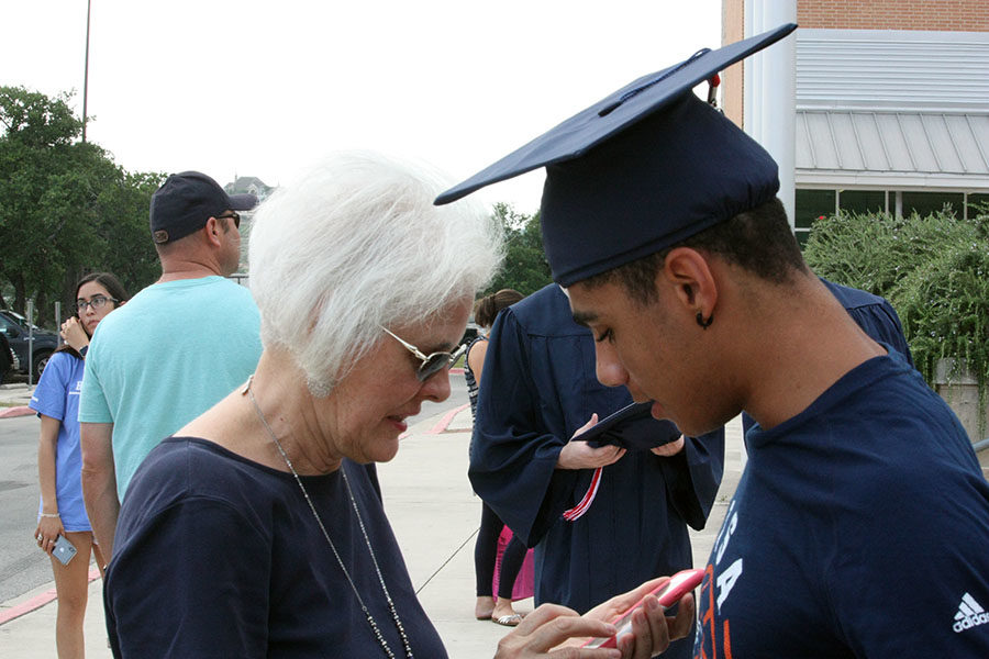 Senior Anthony Valdez plans a group photo with his mom after the senior walk.