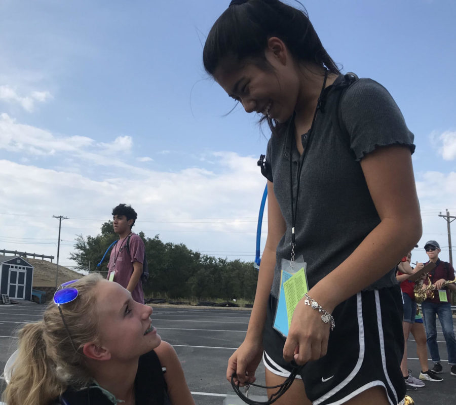 Before band rehearsal begins, sophomore Emily Armstrong passes out marching coordinate sheets to her fellow freshman saxophonist, Sayde Jackson. Armstrong led her peers at practice by helping adjust marching form and guiding new band members. 