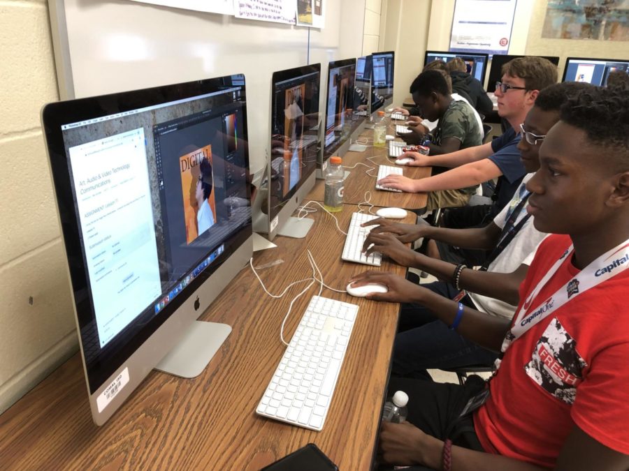 Freshman Isaiah Hackett and classmates design magazine posters in graphic design during fourth period. 