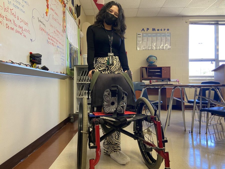 After wheeling in her school books and folders, senior Presley Berry poses with her temporary book bag. She borrowed the wheelchair from the theatre departments prop closet.