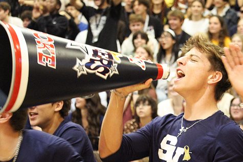 Varsity football player Weston Ross chants with a cheerleaders megaphone.