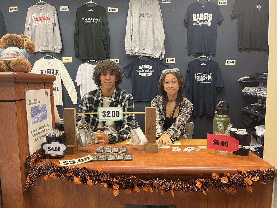 Two students work at the Valley Student Store to sell merchandise to customers.