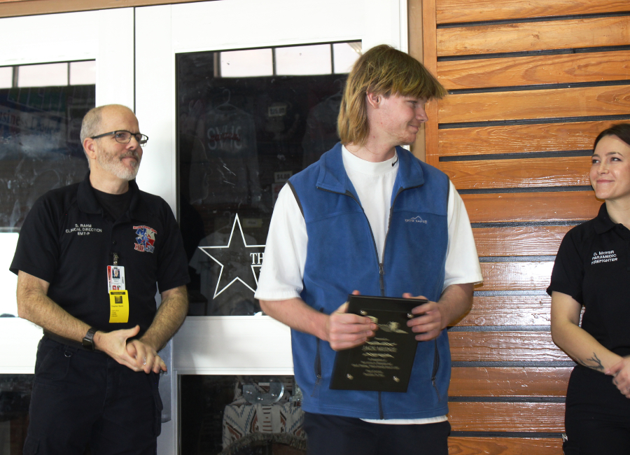 After receiving a plaque Wednesday from Stephan Rahm, clinical director for Bulverde Spring Branch Fire & EMS, senior Jack Mudge gets congratulations from EMT/paramedic D. Moyer. Moyer was among the emergency medical personnel who responded to the call for a heart attack where Mudge performed CPR and saved a mans life.