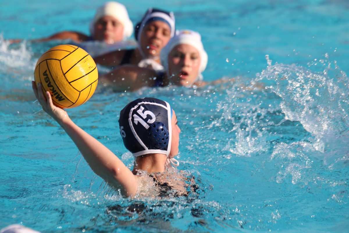 Number 15, freshman, Haylee Kaeding has the ball looking to pass while the defending team Pieper is swimming up to her. Kaeding is not only in waterpolo but is also a a cheerleader. 
