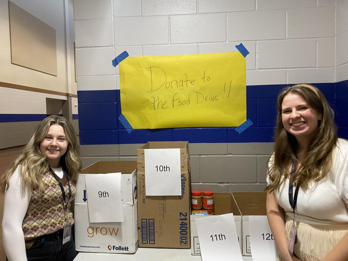 STUCO Vice-President Lily Haider and Historian Sydney Rakowitz stand by the donation stations, located outside the library.