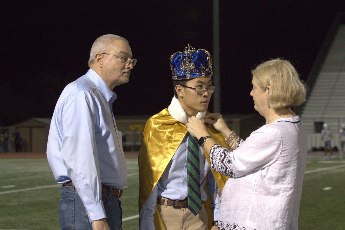 Senior spirit master Thomas Barton has his mom clip on his cape after winning homecoming king. This is the second year in a row Barton has won a position on homecoming court.