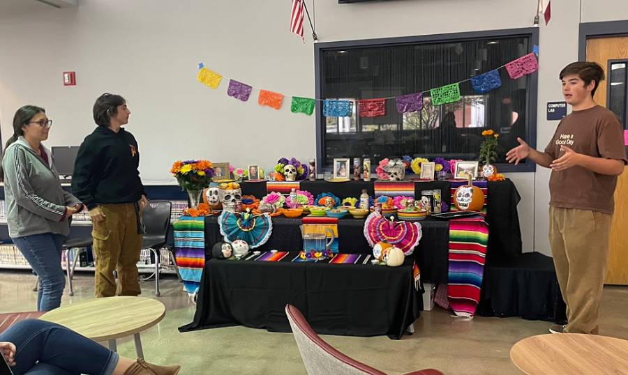 Spanish four students created their own ofrendas in the library, juniors Talan Fuller, Alec Suarez, and Natalie Maille practice presenting the ofrenda before their major grade assessment. 