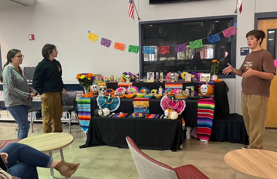 Spanish four students created their own ofrendas in the library, juniors Talan Fuller, Alec Suarez, and Natalie Maille practice presenting the ofrenda before their major grade assessment. 