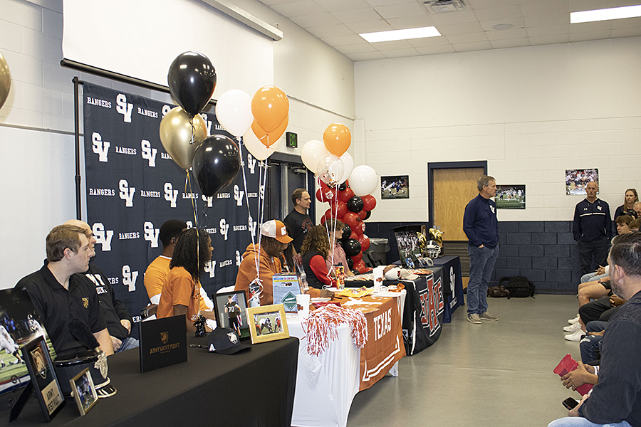 In the fieldhouse meeting room, Coach Larry Hill congratulates Will Mack, Freddie Dubose and Clayton Amaya for signing their letters of intent to play Division I collegiate football.