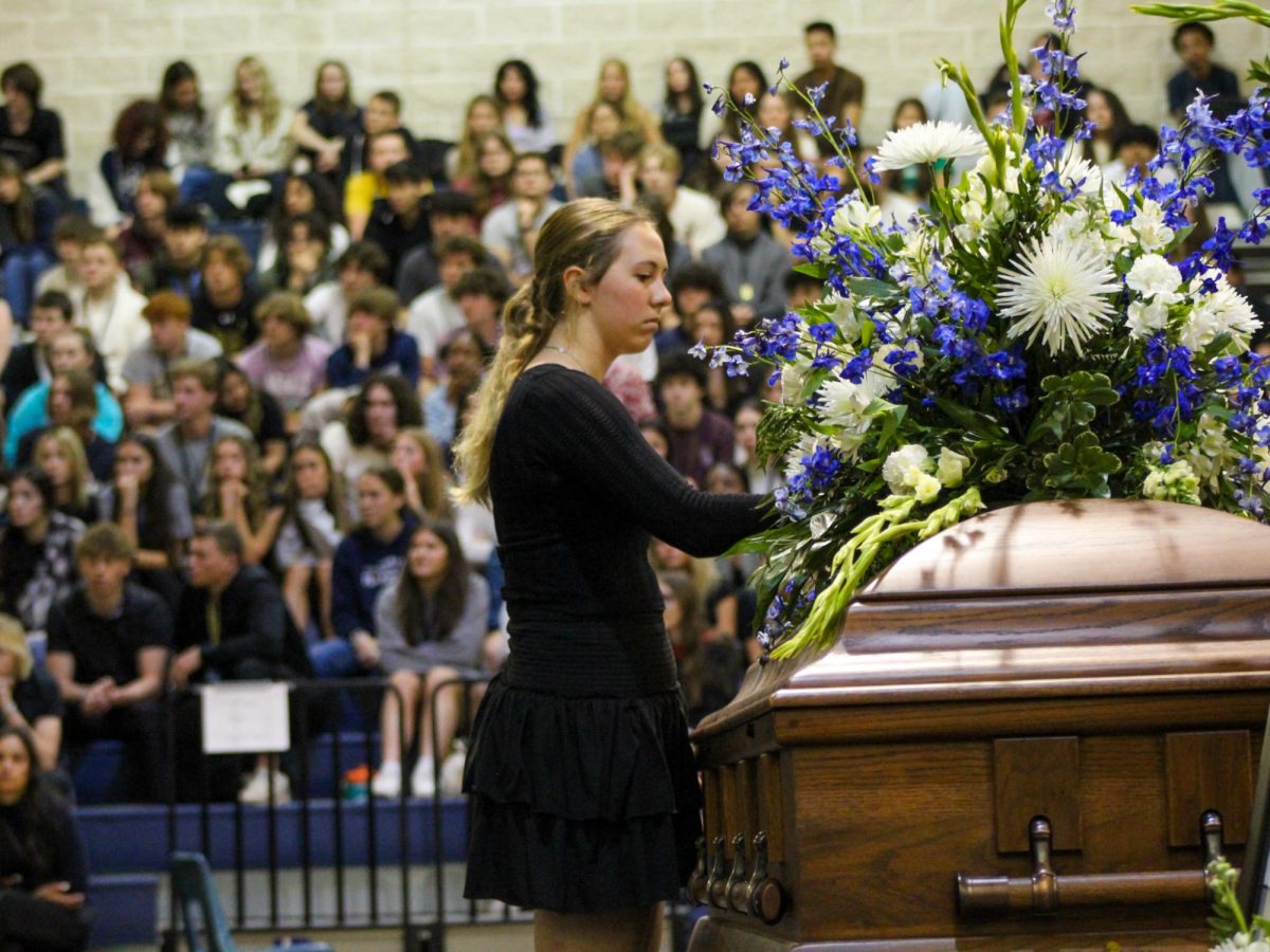 Senior Lily McNett places a flower on the casket during the Shattered Dreams memorial service March 8 to honor her departed friend.