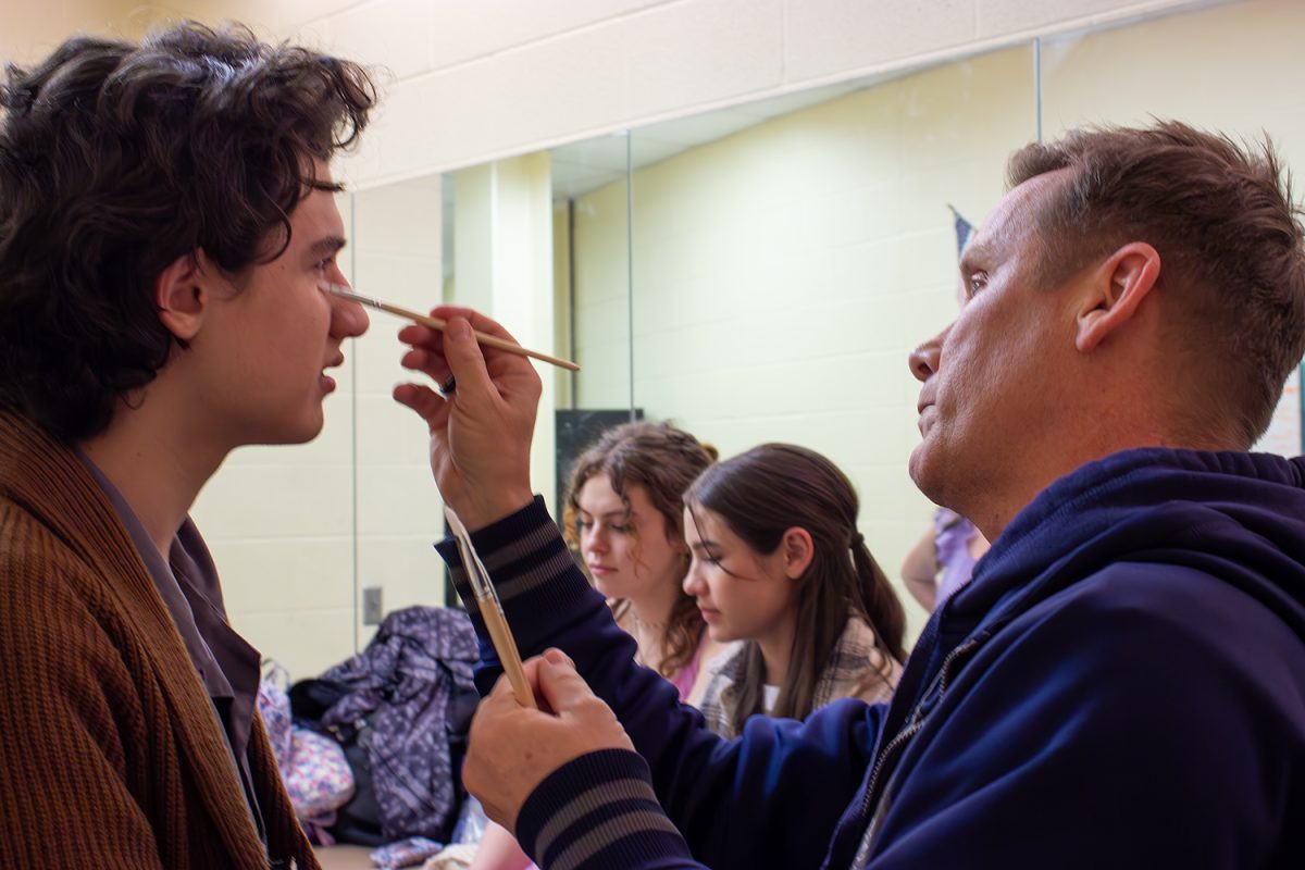 James Berry gets some help with his makeup from technical theater director James Black before a rehearsal for the one-act play Iphigenia. The cast and crew are headed to area after winning district and bidistrict.