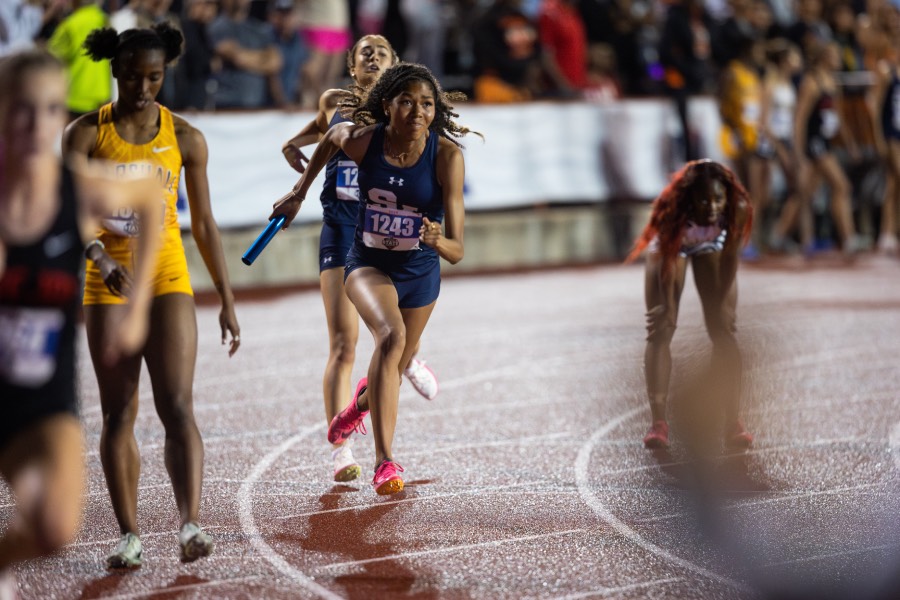 As the baton is handed over, junior Avianna Miller takes off sprinting after freshman Izzy Sutherland completes the first lap of the 4x400 at the state track meet. Miller replaced sophomore Lily Koeing in the second leg. The 4x400 team finished on the podium placing third with a time of 3:46.47. Photo by Davis Kuhn.
