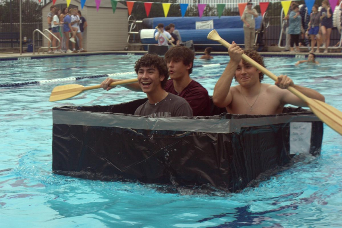 Junior Sean Mendez laughs as is group members junior Travis Collins and Sophomore Tyler Dolly row their boat across the pool. They successfully made it to the finish line.