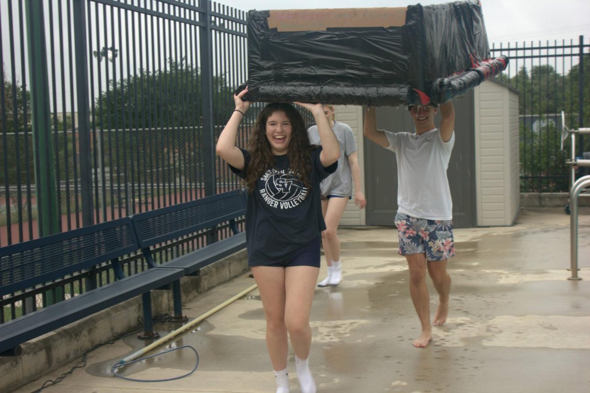 Junior Marlowe Berry carries her boat to the dumpster after successfully making it across the pool. Berrys group added cylindrical cardboard on the sides for extra support.