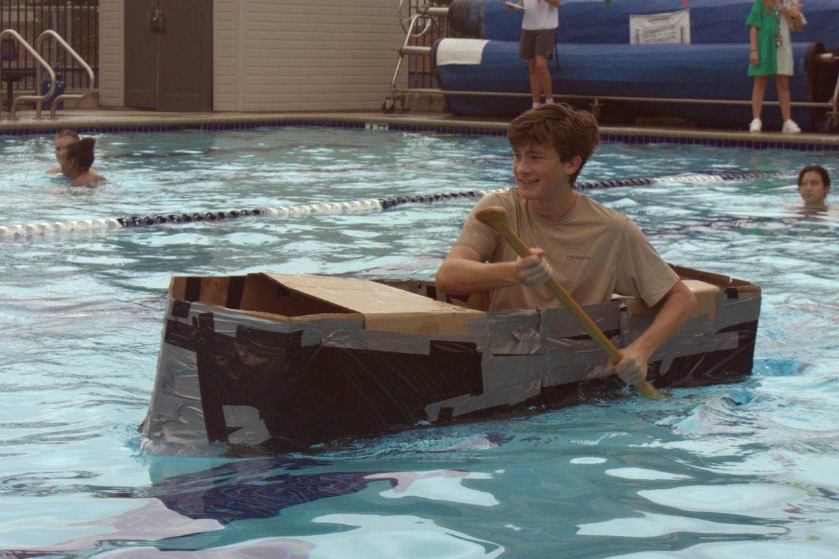 Senior Jack Grieve rows his boat to the finish line after making last minute adjustments. Grieve did not have trash bags on his boat, so junior Marlowe Berry gave him the extra bags she had, and they quickly taped them on. Grieve successfully made it across the pool without sinking.