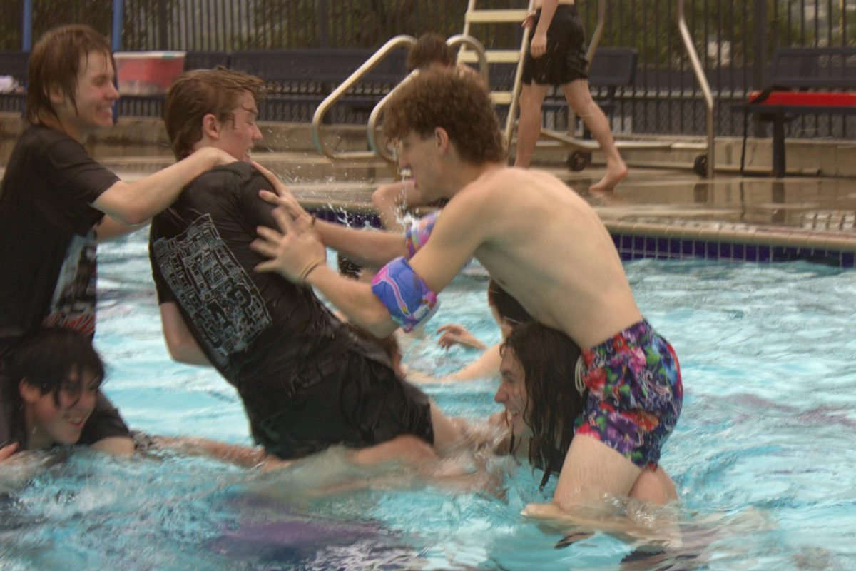 Junior Braeden Wills shoves a student off another students shoulders in a game of chicken fight. After all the boat races were finished, students did not hesitate to jump in the pool.