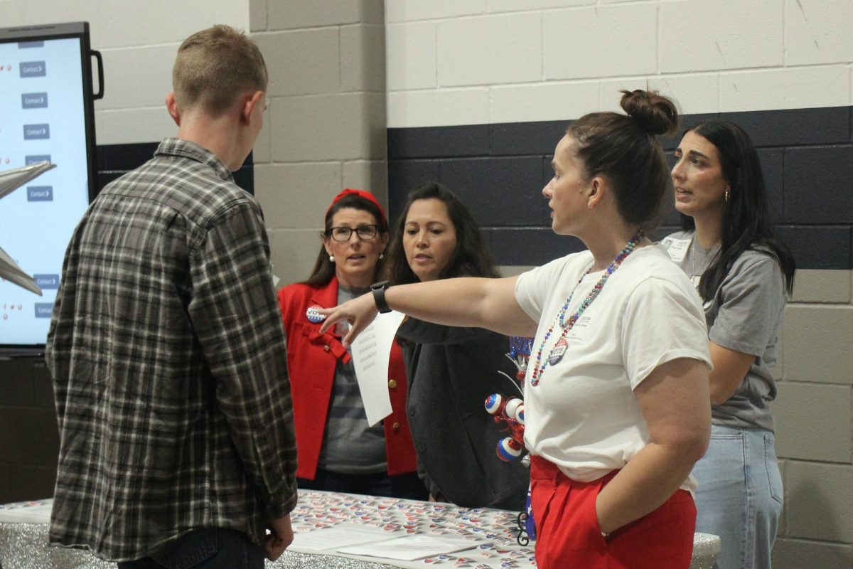 Senior Oscar Silveson talks with parents from the Parent Teacher Association at the vote registration table.