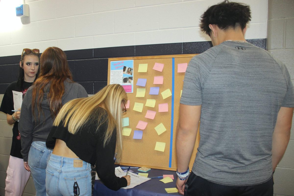 Senior Caleb Sosa reads the post-it notes at the books as mirrors and books as windows station. 