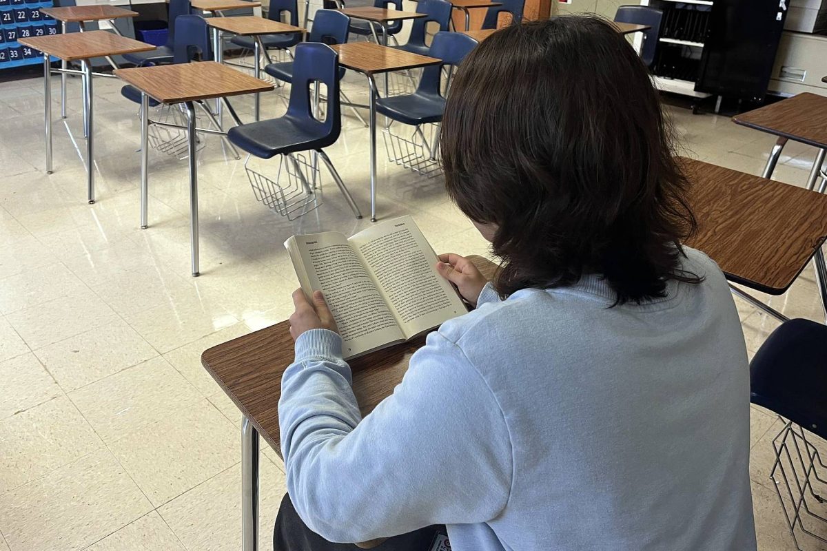 Senior Alec Suarez reads from a classroom copy of Fahrenheit 451 by Ray Bradbury. The book is set in a dystopian society where books and literacy are obsolete.