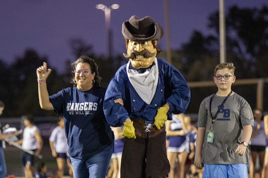 Spring Branch Middle School principal Sally Bratton gets escorted down the field by her campus's mascot and representative.