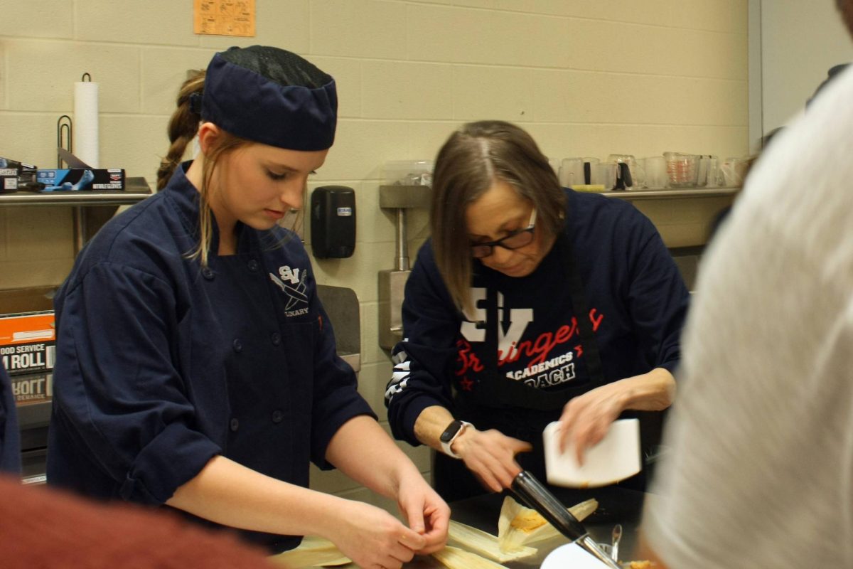 Junior culinary student Audrey Mcilwain and ASL teacher Claudia Barthuly fill the masa on the corn husk.