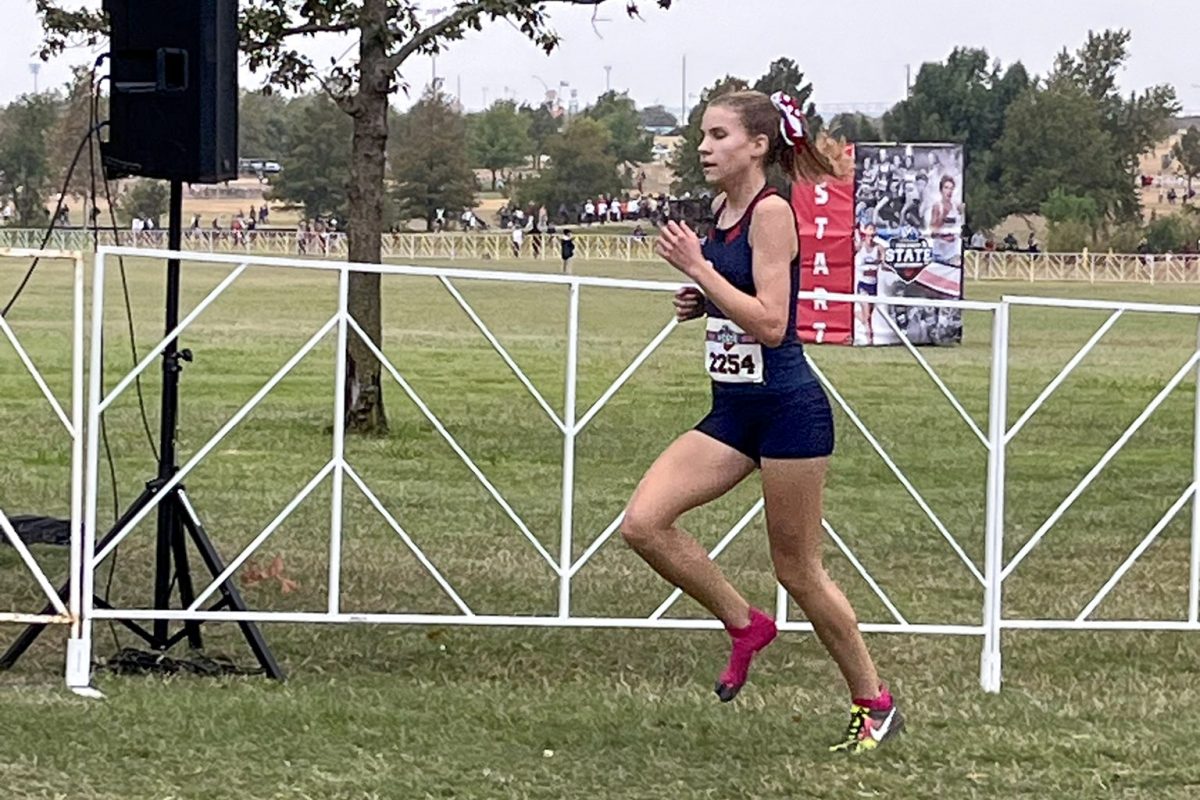 Heading to a third place state finish, freshman Brady Solansky runs with one shoe on after losing the other in the first 100 meters on gravel. She finished the rest of the race mostly on grass. (Photo by Marsha Hammond)